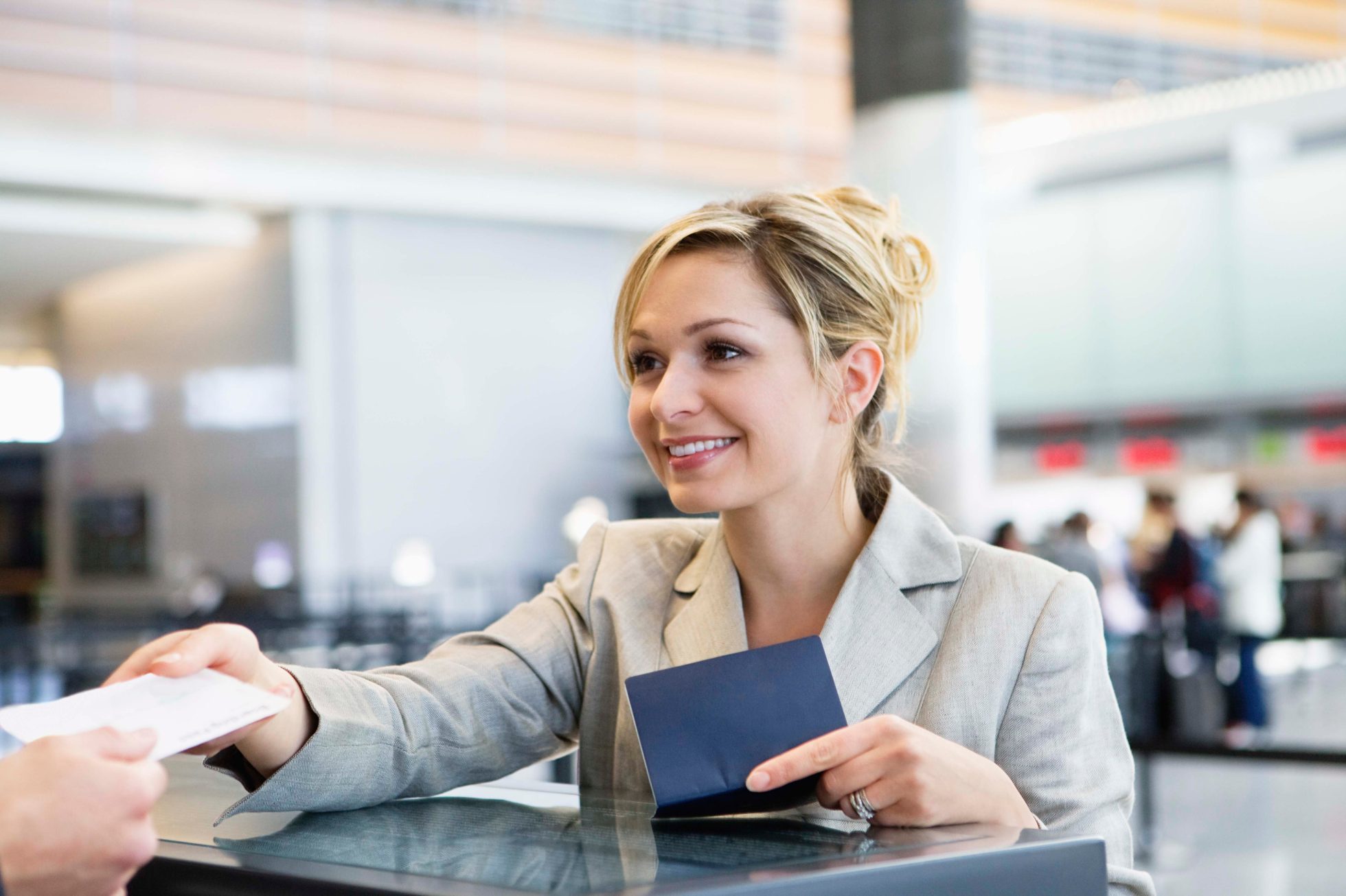 A young woman hands over her passport at the airport check-in counter.